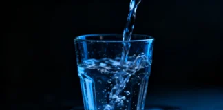 A glass Overhydration Dangers with water on a dark background symbolizing the dangers of drinking too much water