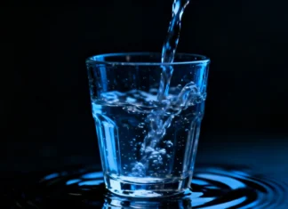 Overhydration Dangers: Why Drinking Too Much Water Is Worse Than Mild Dehydration A glass Overhydration Dangers with water on a dark background symbolizing the dangers of drinking too much water