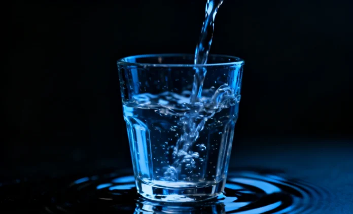 A glass Overhydration Dangers with water on a dark background symbolizing the dangers of drinking too much water