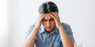 Person holding their head in pain next to a glass of water — dehydration headache symptoms and relief