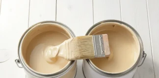 Two open paint cans showing Latex Paint vs Oil-Based Paint side by side with a paintbrush on a white wooden surface
