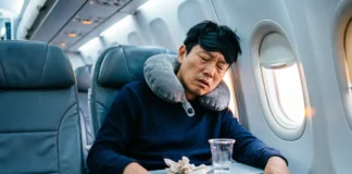 Exhausted traveler experiencing window seat sleep problems on long flight