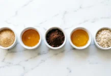 Easy DIY Body Scrub Recipes with Coconut Oil for Glowing Skin Flat lay of diy body scrub recipes ingredients including sugar, coconut oil, coffee grounds, and honey on marble