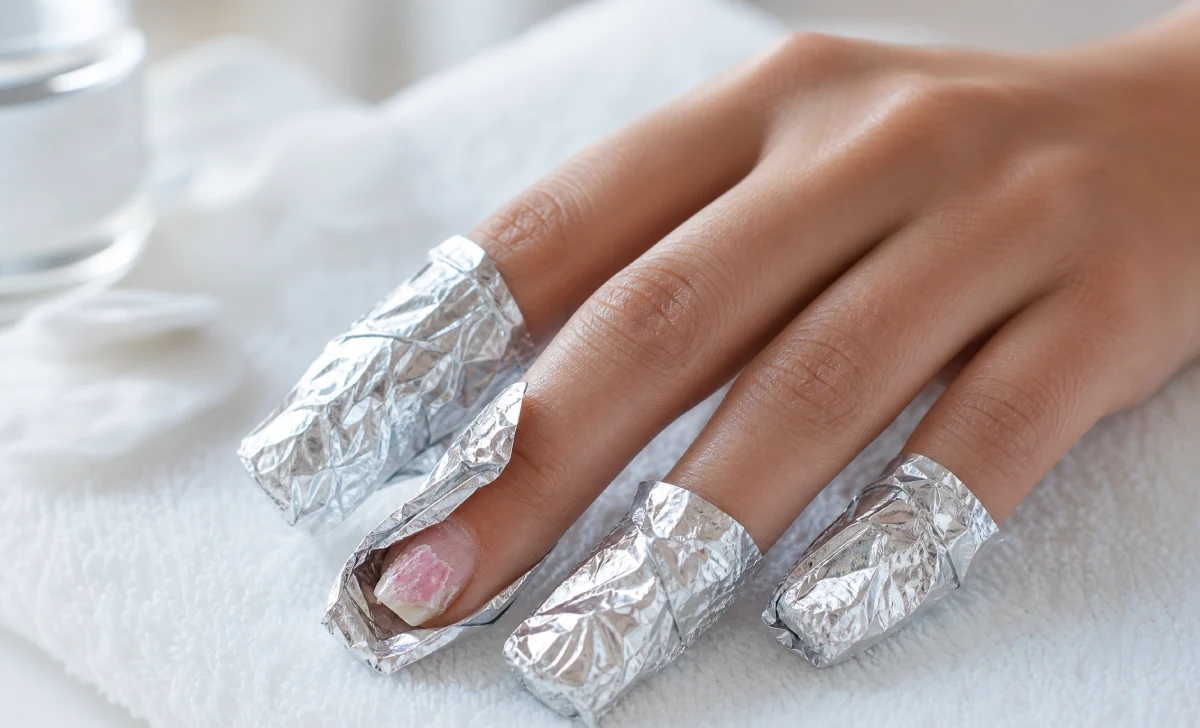 Fingers wrapped in acetone foil showing safe removal method for gel vs acrylic nails without damaging natural nail plate