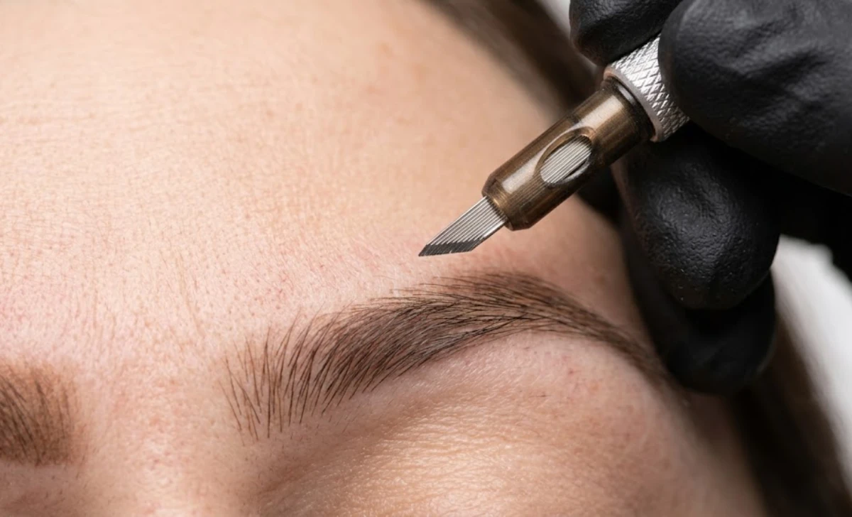 Artist holding microblading hand tool above eyebrow area close up