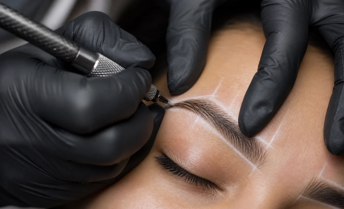 Artist mapping and microblading eyebrows during a salon session