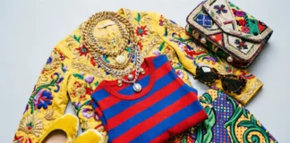 Maximalist outfits flat-lay with mixed prints, bright colors, embroidered jacket, striped top, patterned trousers, and stacked accessories inspired by Iris Apfel.