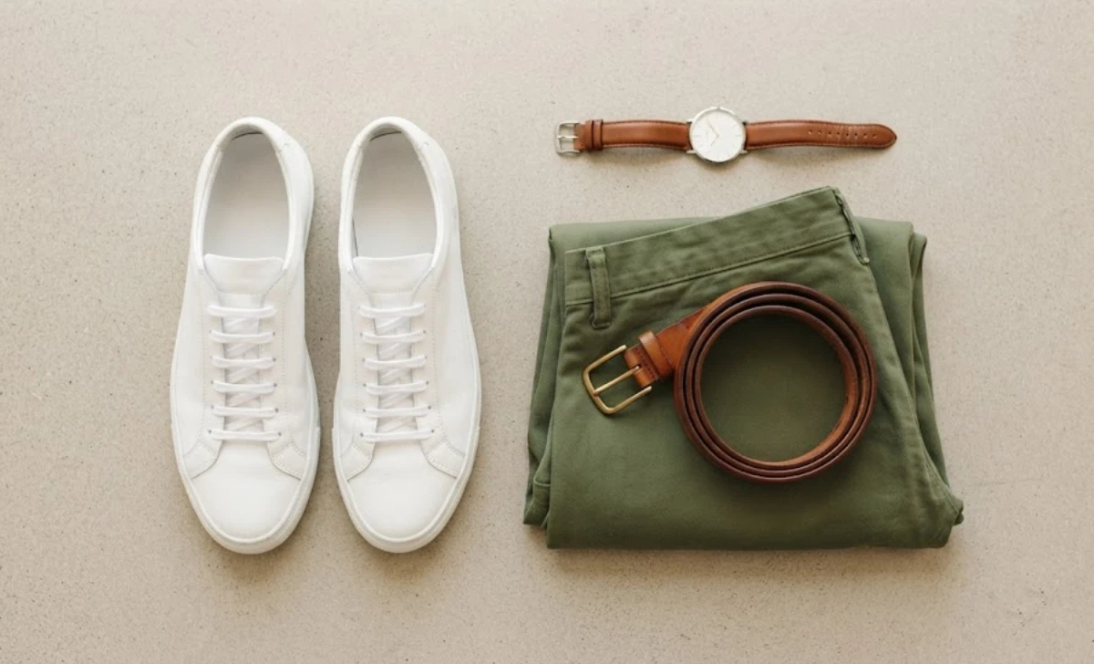 White sneakers and brown belt styled as accessories for a green pants outfit