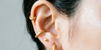 Types of ear piercings shown on woman's ear including lobe, helix, and tragus