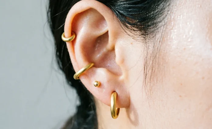 types-of-ear-piercings-guide Types of ear piercings shown on woman's ear including lobe, helix, and tragus