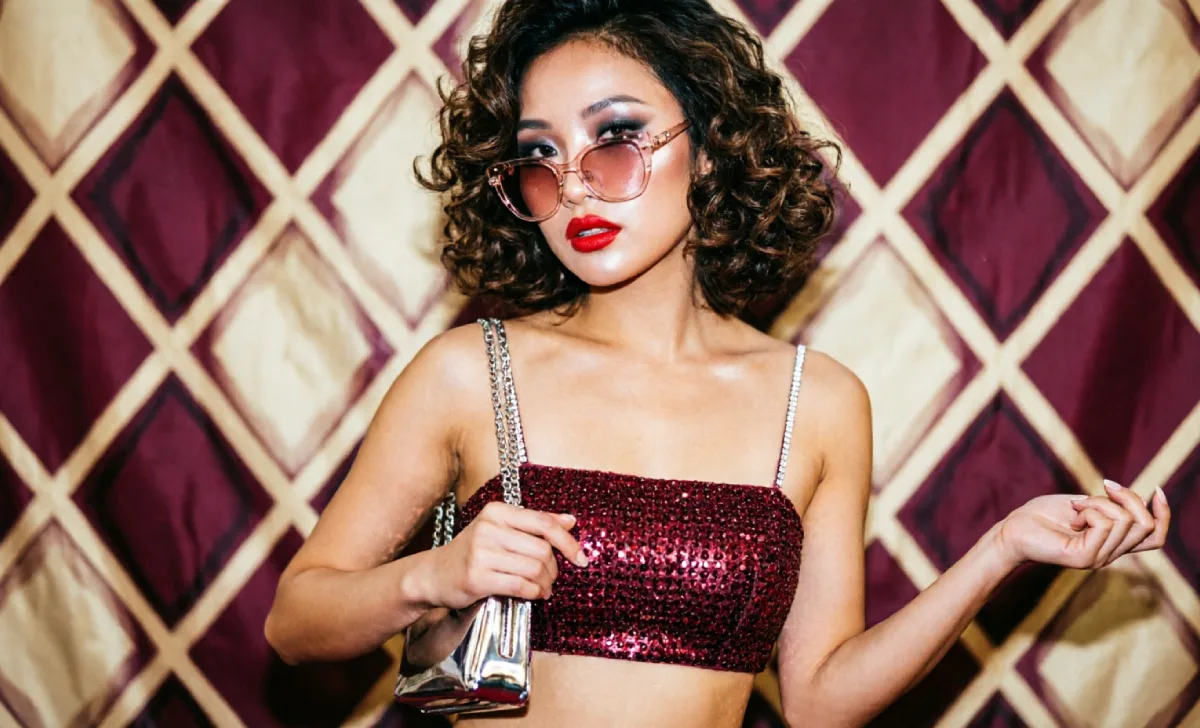 Red carpet-inspired y2k fashion trends look with a halter top, tinted sunglasses, and metallic clutch bag.